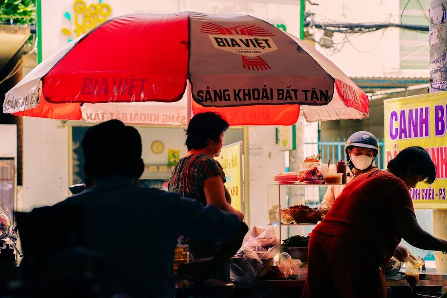 Street food stall under red umbrella at a Ho Chi Minh City market