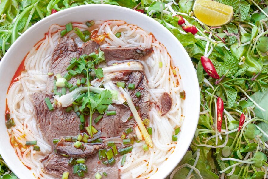 Bowl of Vietnamese pho with beef, herbs, and noodles