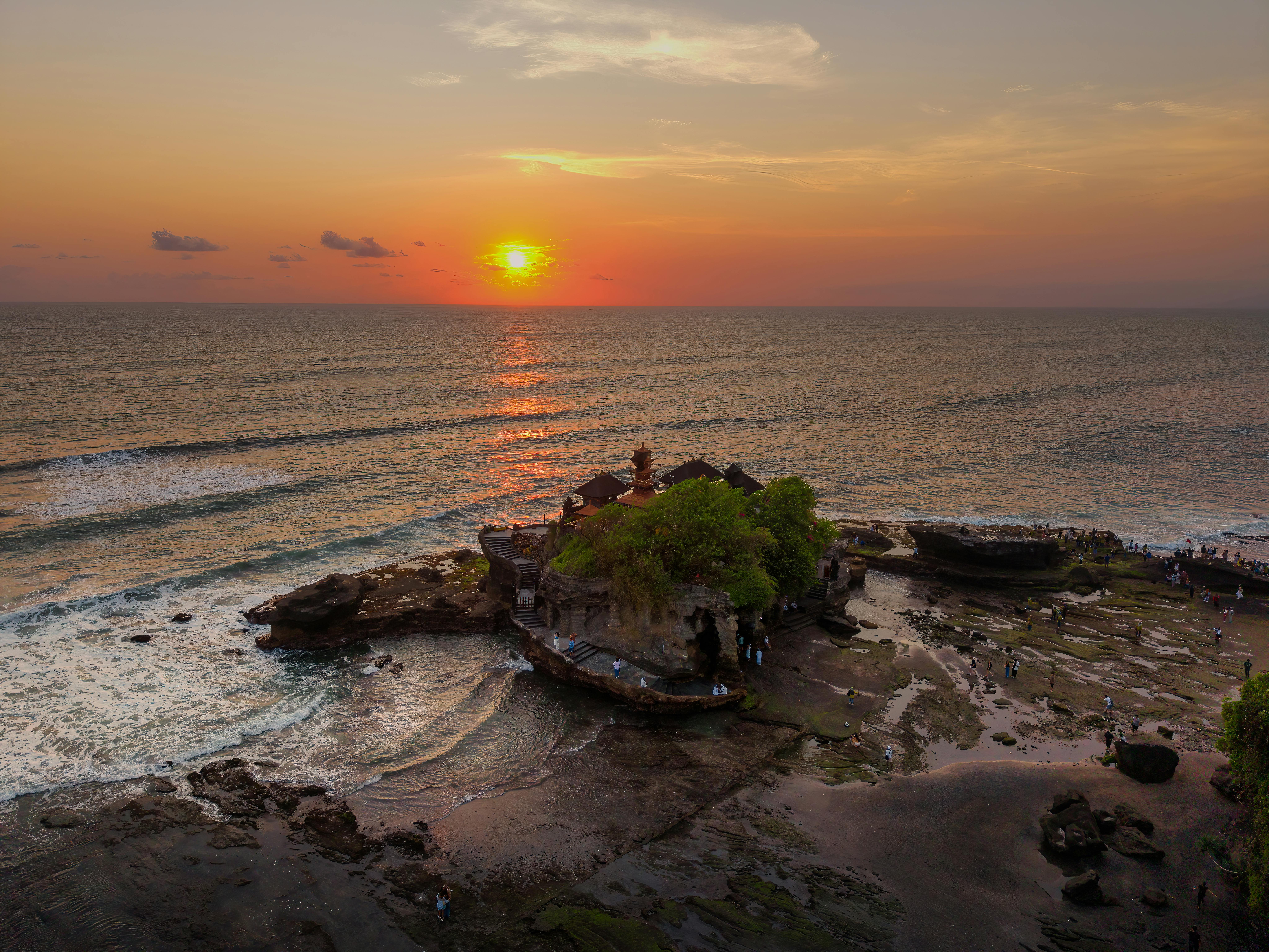Tanah Lot Temple at sunset with ocean waves and golden sky