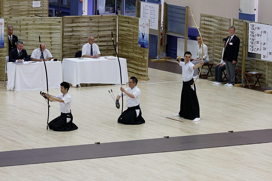 Kyudo archer releasing arrow wearing traditional white and black uniform