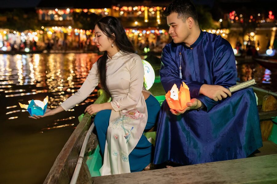 Couple releasing floating lanterns on the river in Hoi An at night