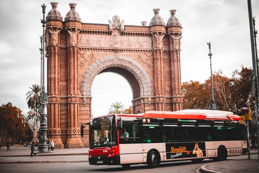 Red TMB city bus passing the Arc de Triomf in Barcelona