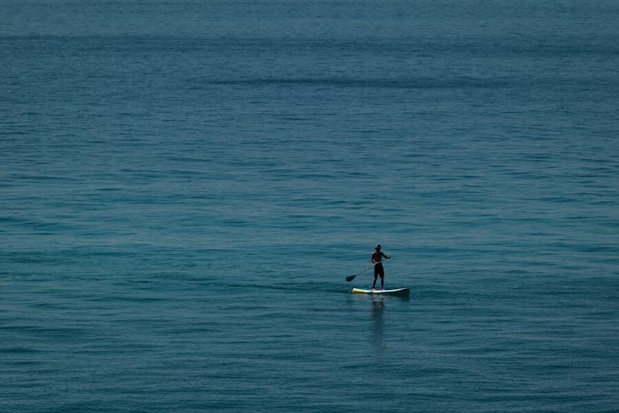 Paddleboarder gliding across calm Mediterranean water