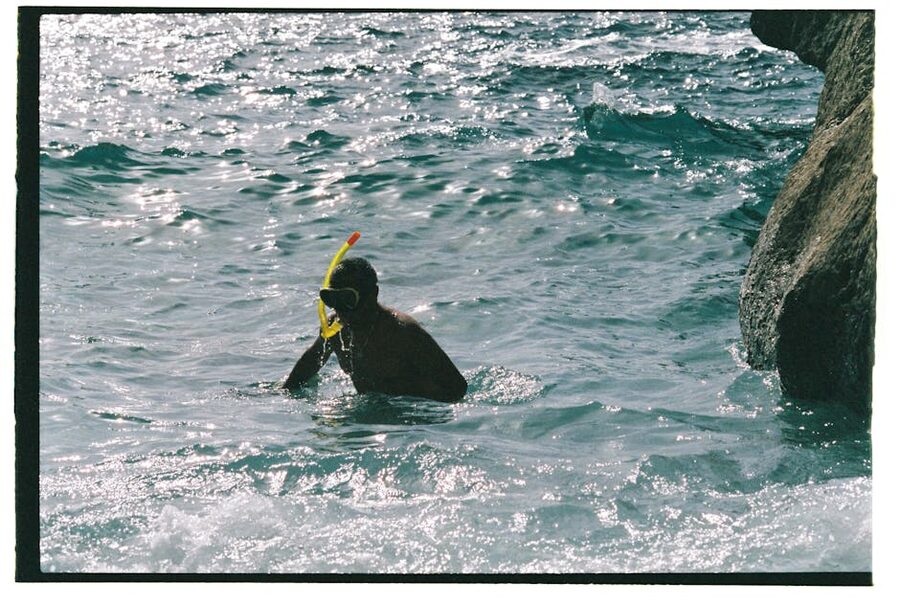 Snorkeler in clear water near coastal rocks