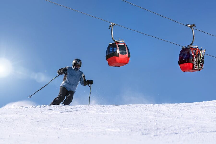 Skier with gondolas overhead against a clear blue sky