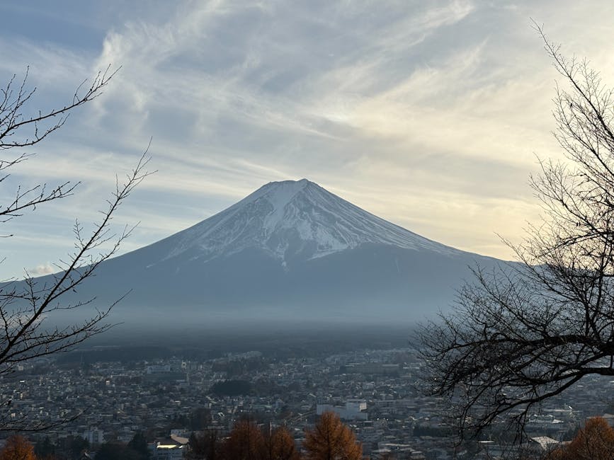 Mount Fuji silhouette at dusk with city lights in the foreground