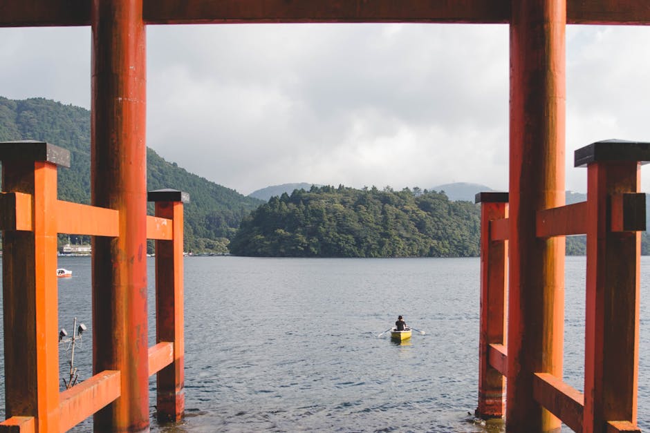 Kayaker paddling under the torii gate of Hakone Shrine on Lake Ashi