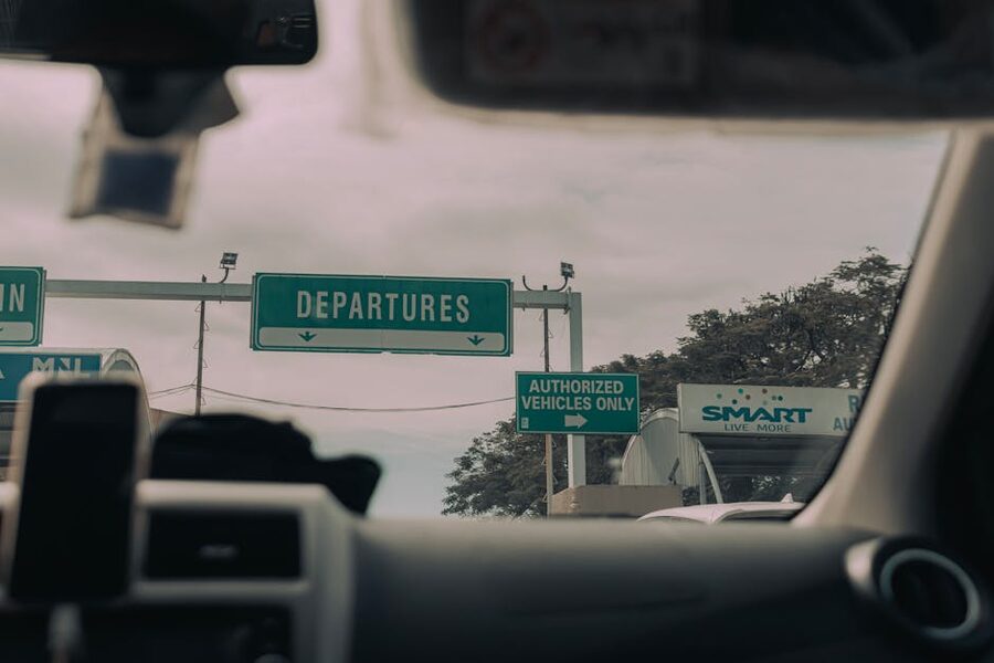 View through windshield of car driving towards airport departure signs