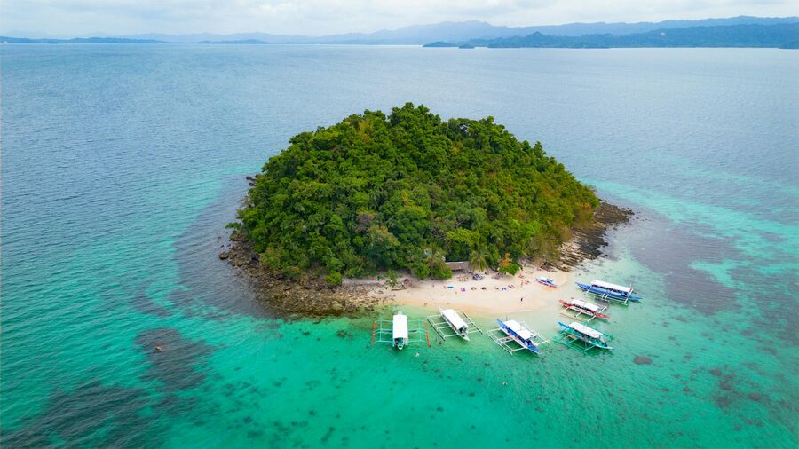 Aerial view of a single lush island surrounded by turquoise water