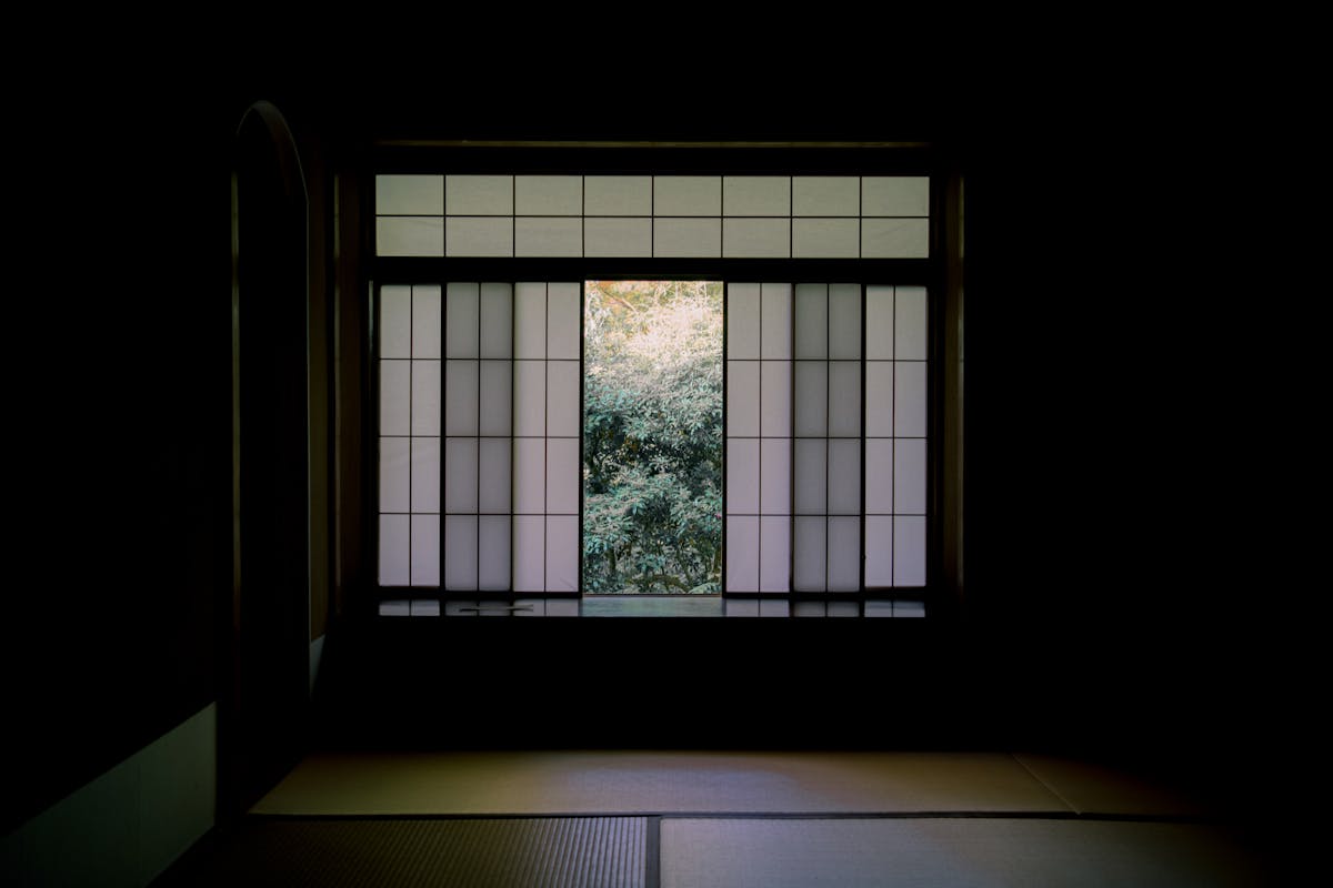 View from inside a traditional Japanese room through shoji paper screen doors to a peaceful garden