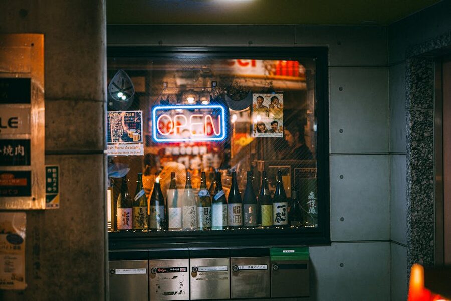 Japanese sake shop window with bottles and neon sign at night