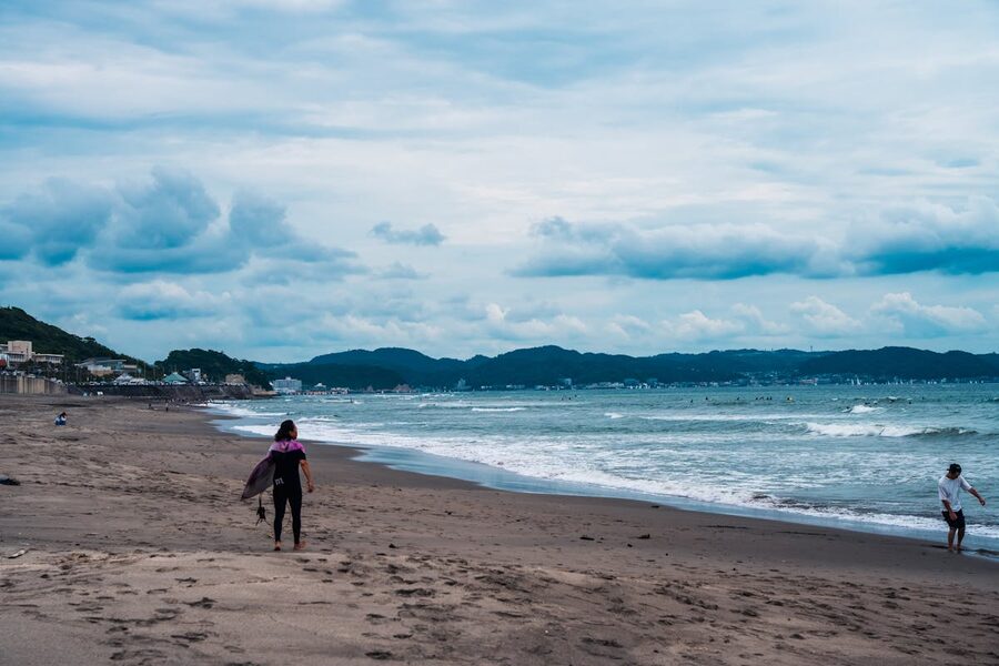 People strolling along Kamakura beach with scenic ocean view