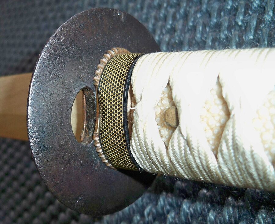 Close-up of Japanese katana tsuba guard, fuchi collar, and tsuka-ito handle wrapping