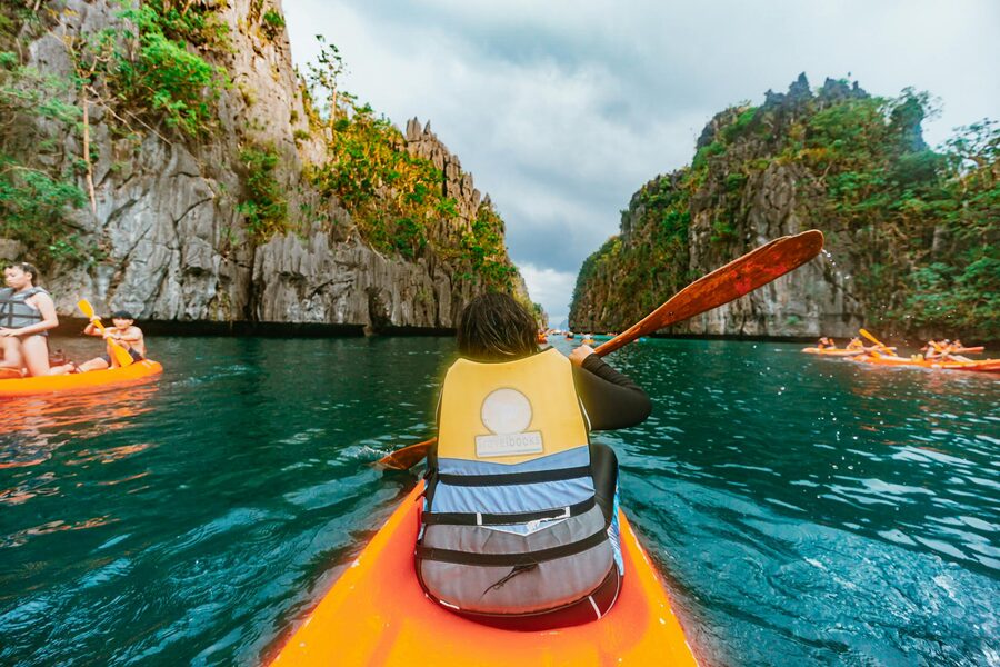 Kayakers paddling through a narrow limestone canyon with turquoise water