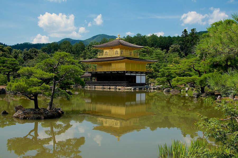 Golden Pavilion Kinkakuji temple reflected in a still pond surrounded by greenery