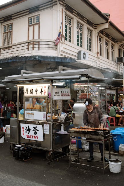 A street vendor prepares satay skewers on a grill in Kuala Lumpur