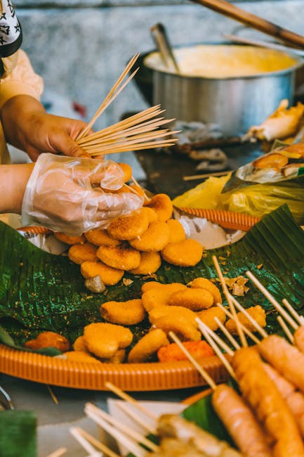 A street vendor prepares skewered fried snacks at an outdoor market in Kuala Lumpur