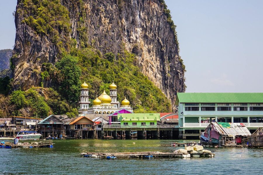 The floating village of Koh Panyi with colorful houses and mosque beneath a massive cliff