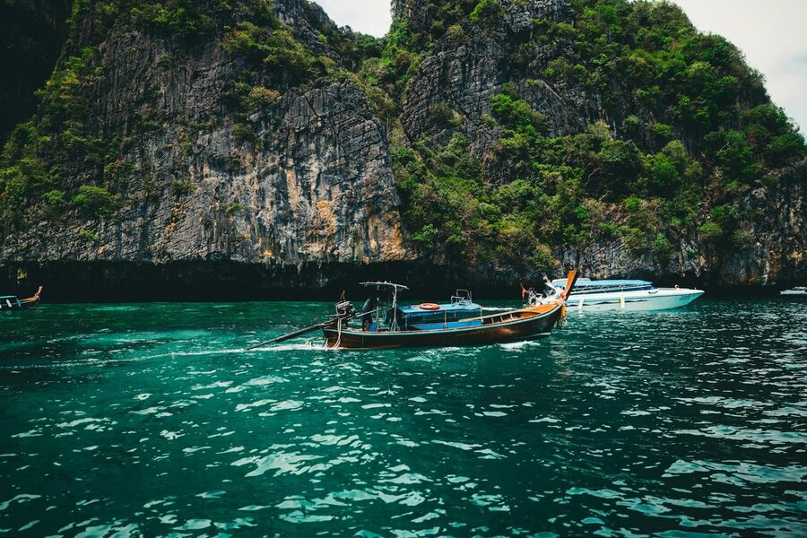 Longtail boat on emerald green waters against limestone cliffs