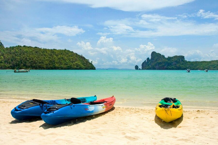 Colorful kayaks lined up on a pristine Thai beach with turquoise water