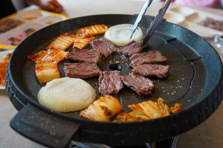 Korean BBQ grill with beef onions and kimchi as side dish