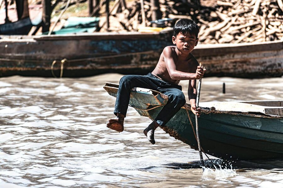 A young local boy navigating a wooden boat in Kampong Phluk