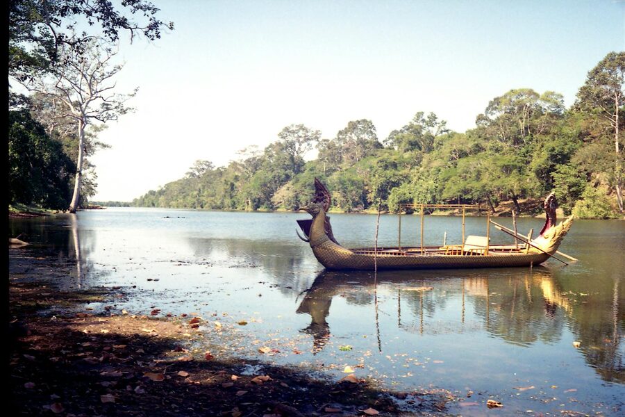 A traditional carved boat docked on a riverbank in Siem Reap