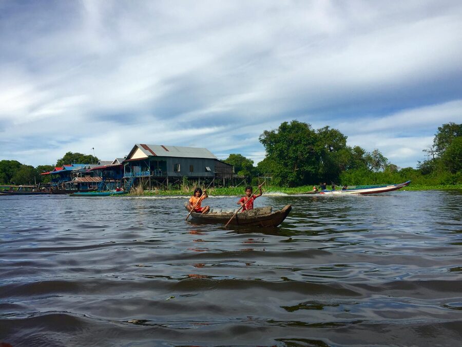Two children rowing a wooden boat on the river