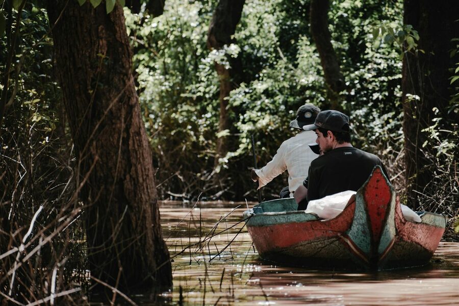 Small boat gliding through flooded mangrove forest at Kampong Phluk
