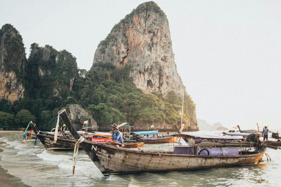 Traditional Thai longtail boats with towering limestone cliffs in Krabi background