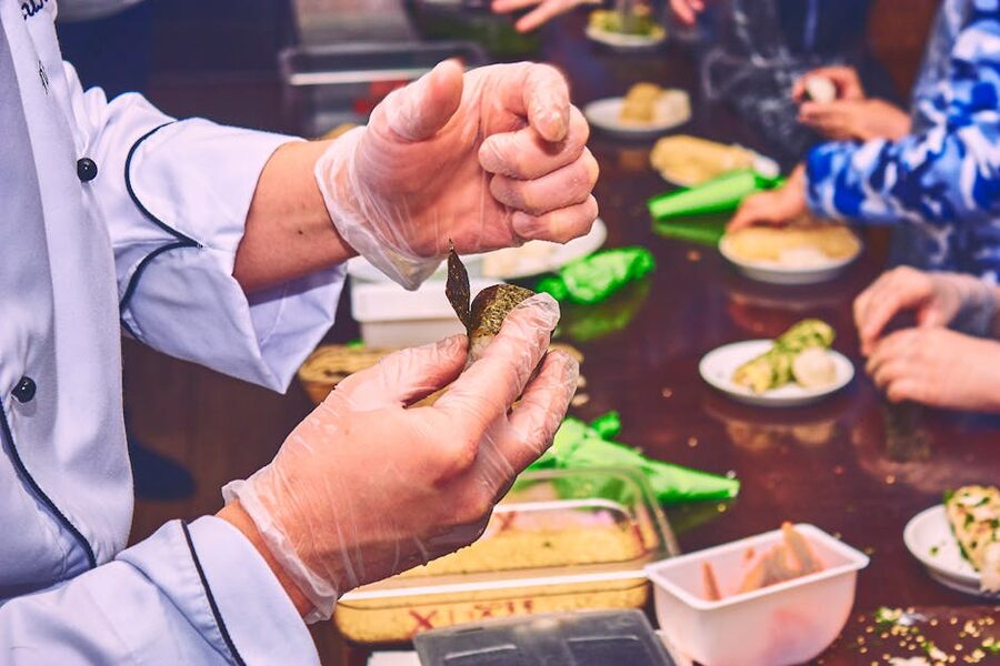 Chef demonstrating a maki roll technique at a cooking class counter