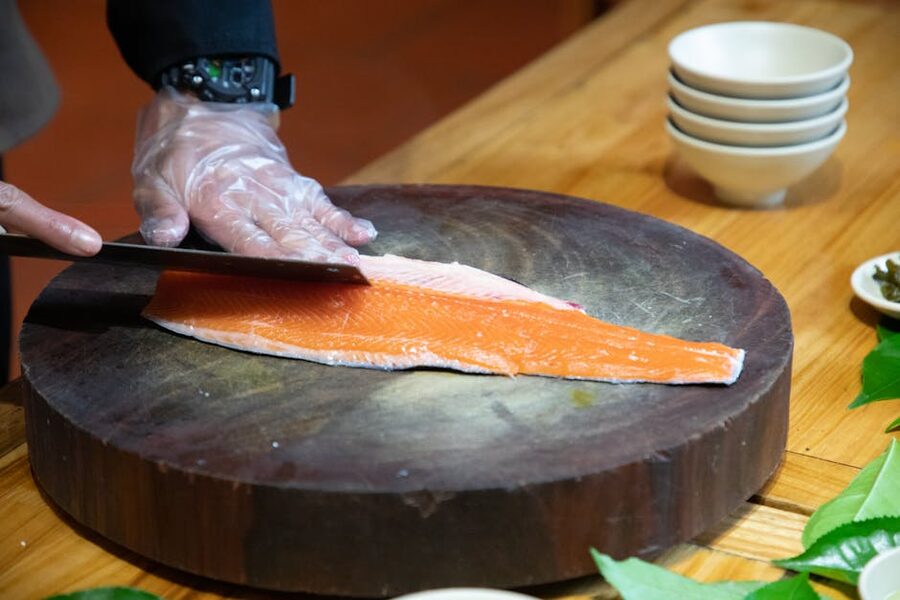 Chef slicing fresh salmon on a wooden board