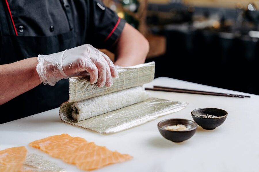 Hands rolling a sushi roll on a bamboo mat