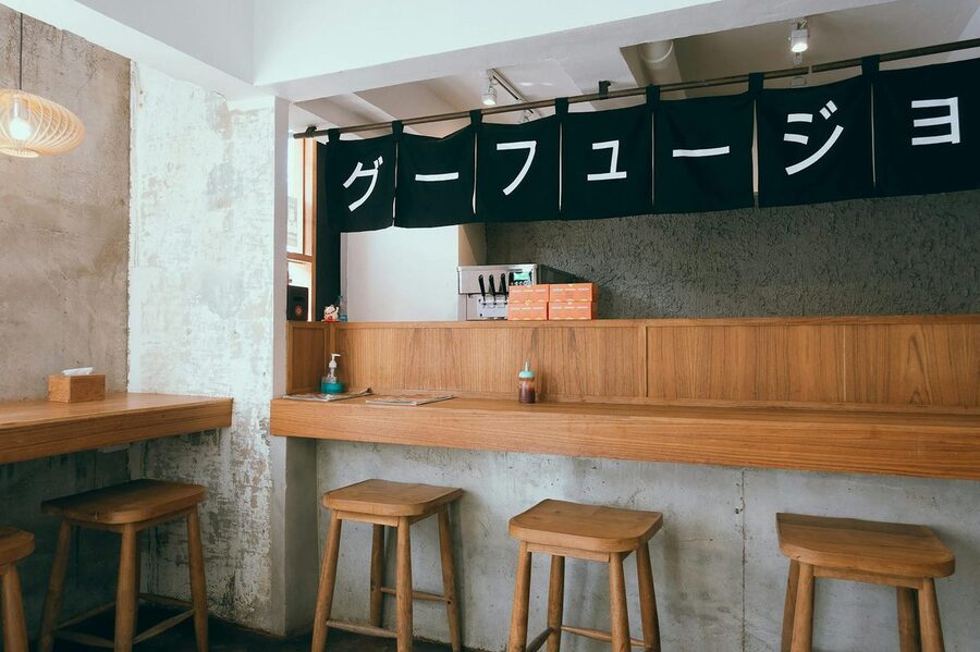 Warm izakaya interior with wooden stools and minimal decor