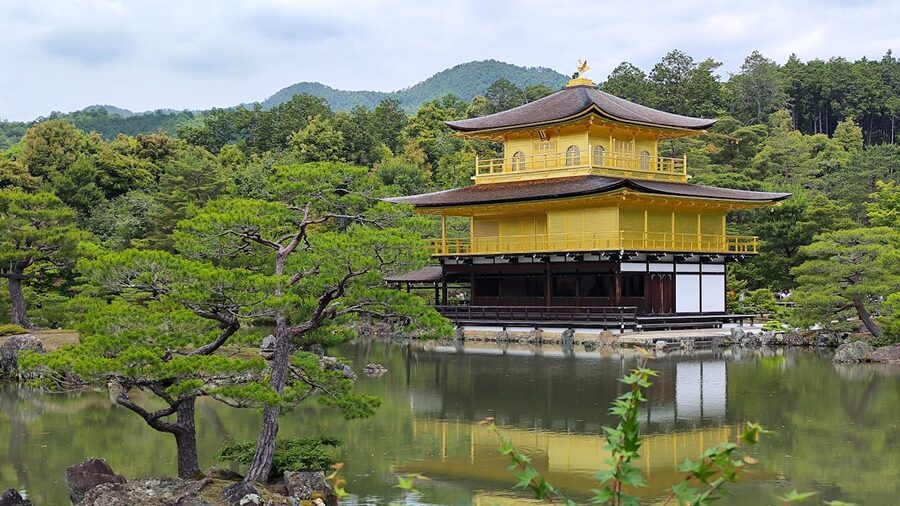 Kinkaku-ji Temple in Kyoto reflecting in a tranquil pond surrounded by greenery