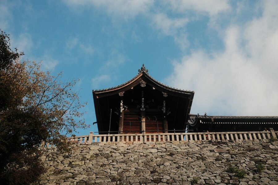Traditional wooden temple roof architecture against blue sky in Kyoto