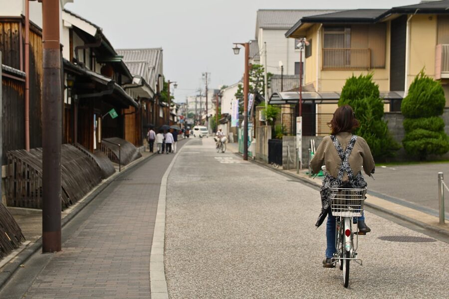 Woman rides a bicycle down a tranquil street in Kyoto Japan