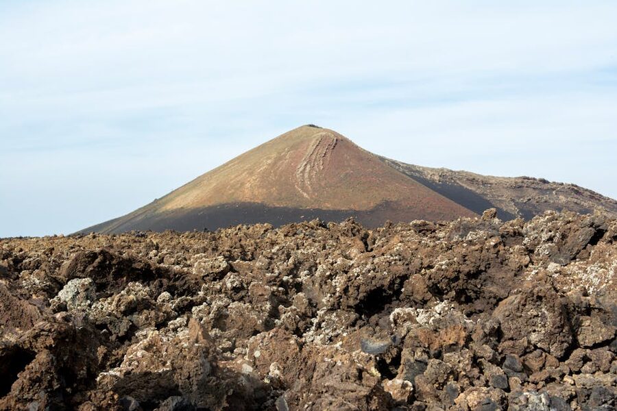 Lanzarote volcano with brown volcanic rocks foreground