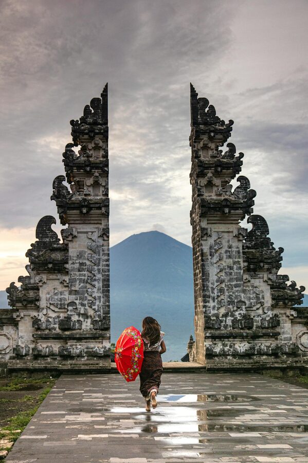 Woman with an umbrella walking toward the Lempuyang Temple gate in Bali