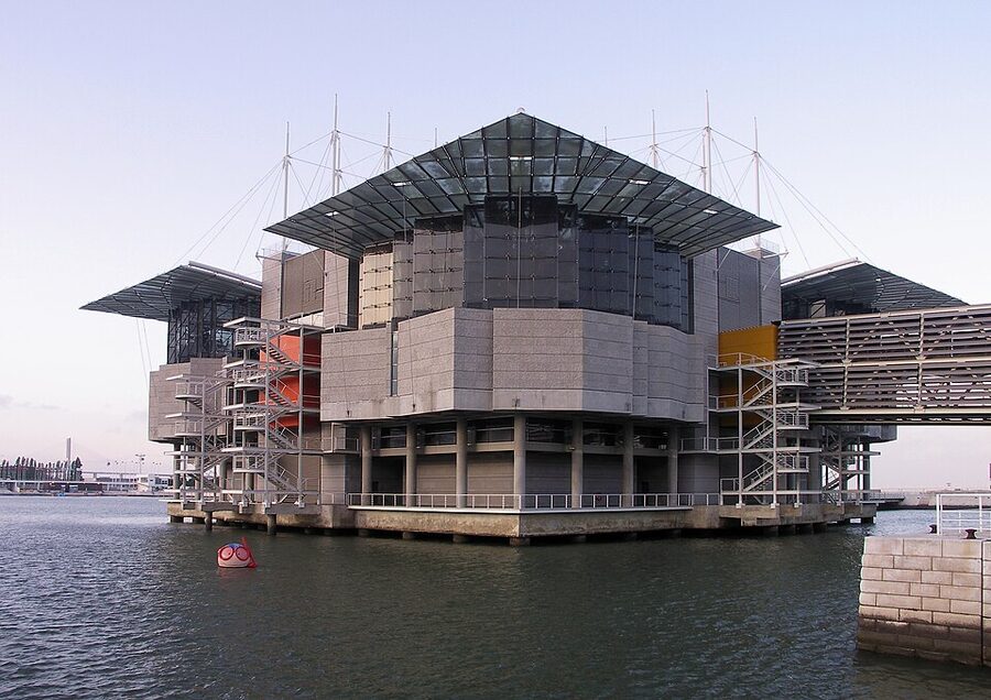 Oceanário de Lisboa concrete building floating on water with footbridge