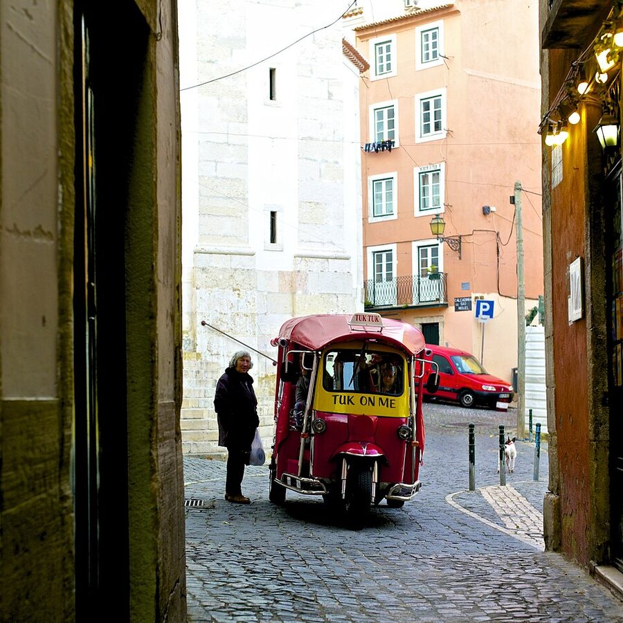 Tuk-tuk in Alfama district Lisbon narrow street with white walls