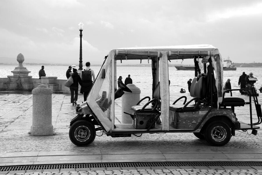 Electric tuk-tuk near Lisbon waterfront in black and white