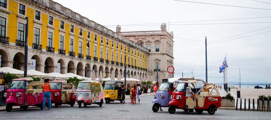 Tuk-tuks parked in a Lisbon square with historic city building backdrop