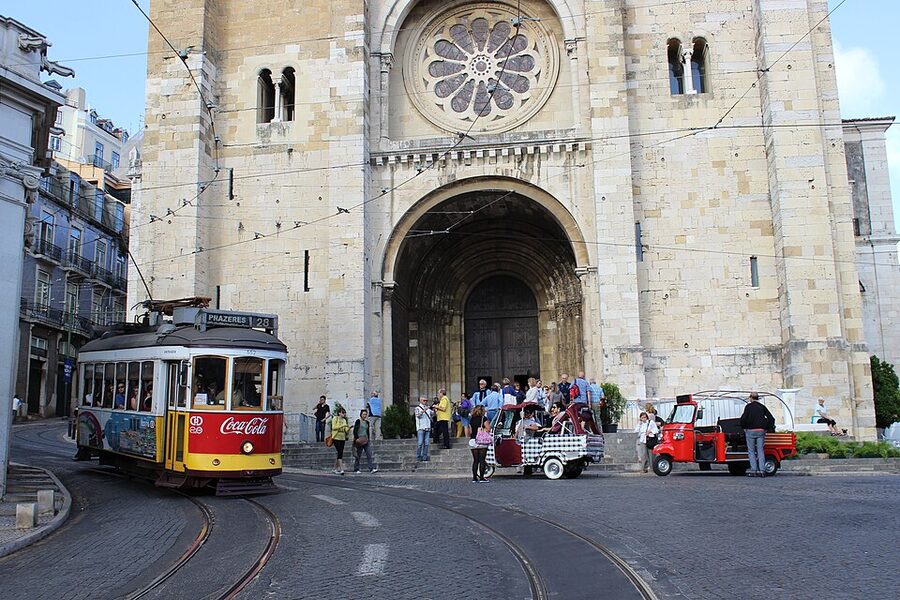 Tram 28 and tuk-tuk taxis sharing a Lisbon street