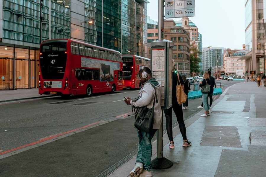 London bus stop with people waiting and double-deckers passing