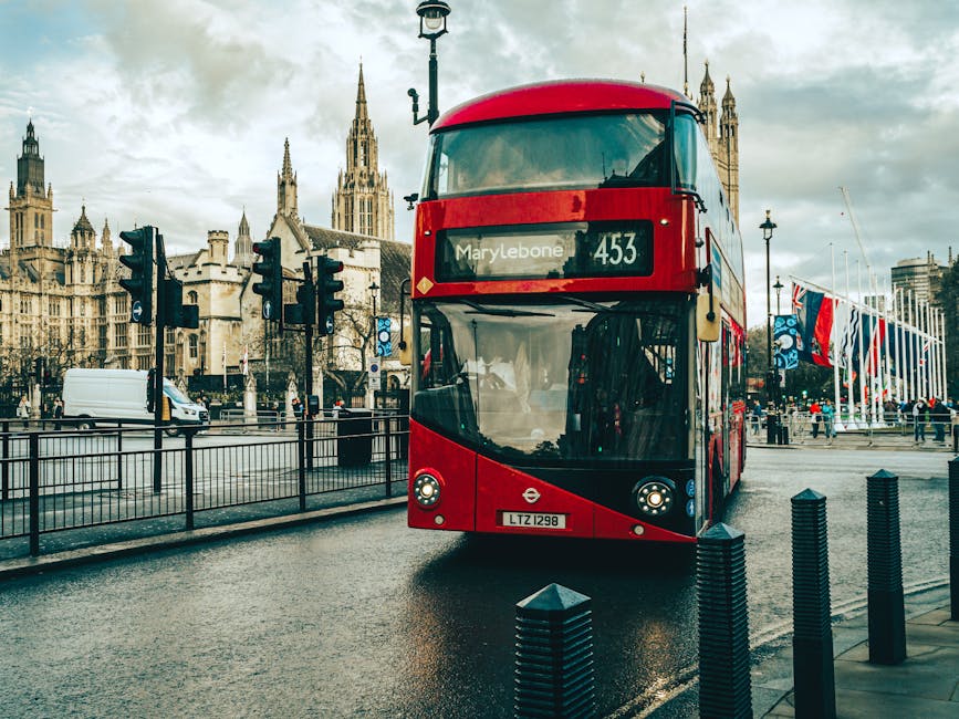 Red bus passing London landmarks on a rainy day