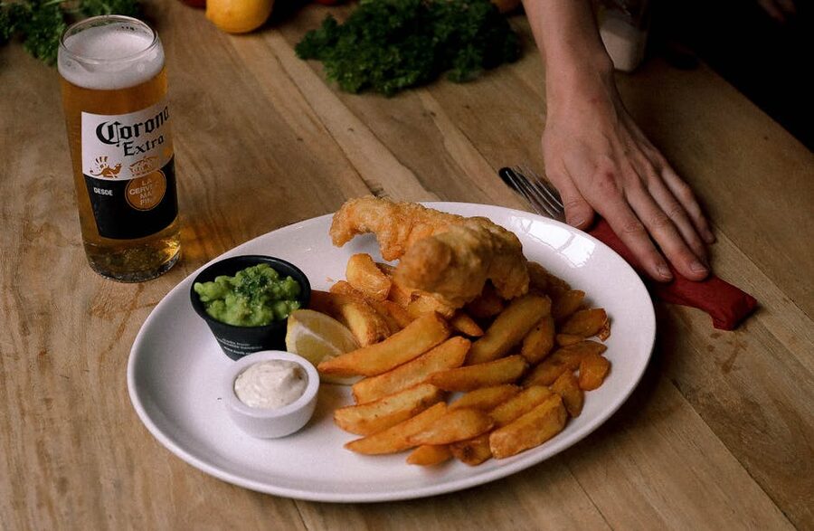 Fish and chips with a pint on a wooden pub table