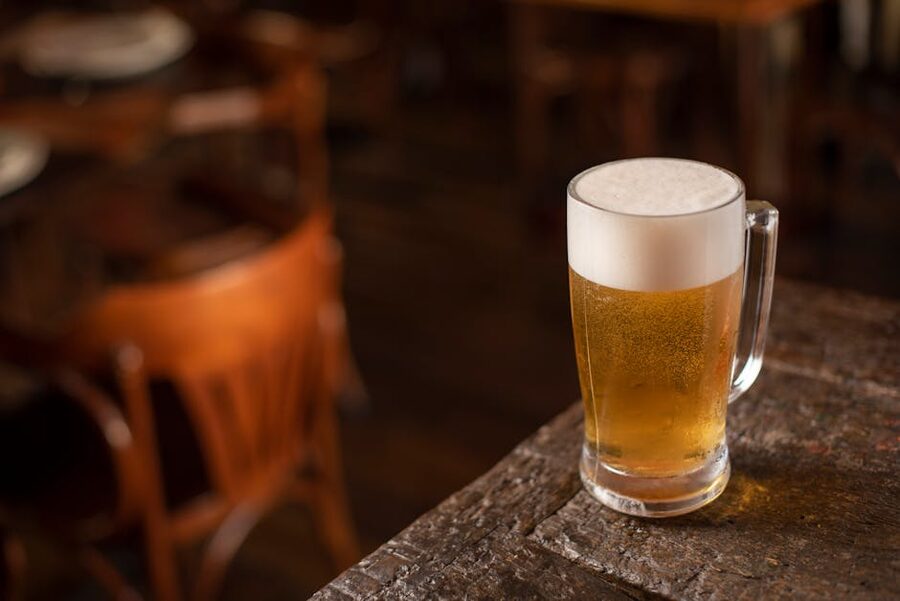 Frothy pint of ale on a wooden pub table