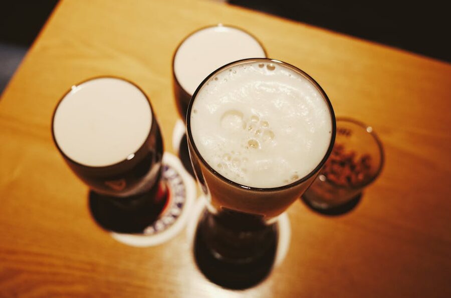 Pints of beer with foam on a wooden table