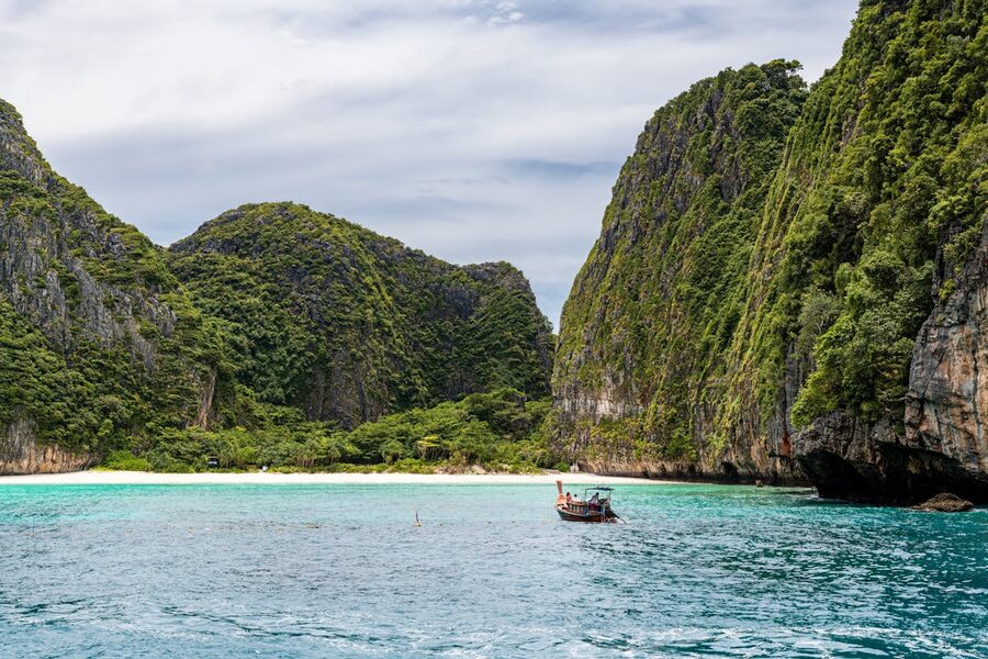 Traditional Thai longtail boat near dramatic limestone cliffs in Phuket